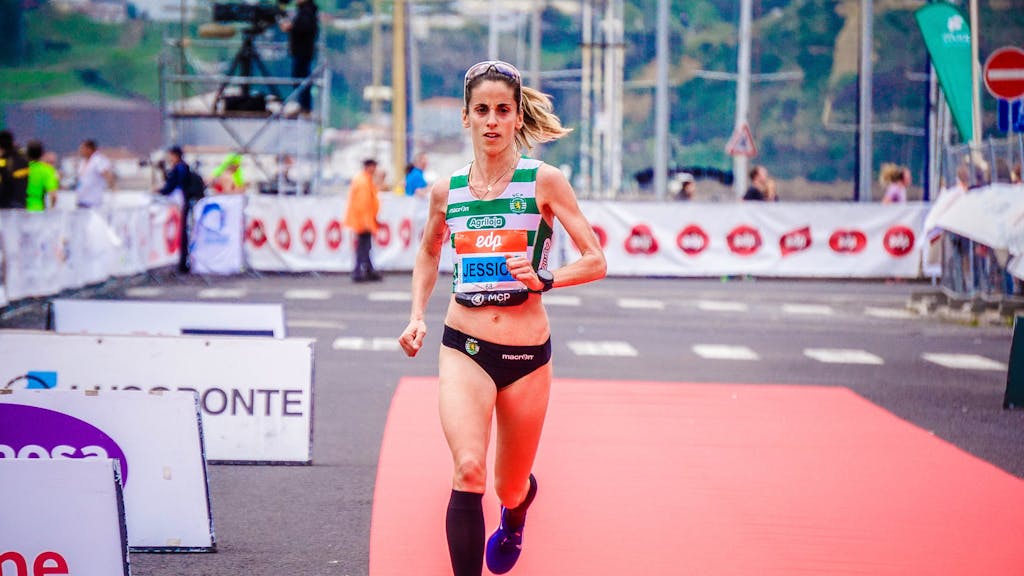Focused female athlete crossing the finish line during an outdoor marathon race.